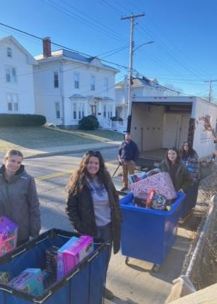 Students and volunteers load toys and gifts into a box truck